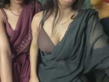 Media: Video of two South Asian women in traditional maroon and black saris, showcasing their medium-sized breasts and long hair, against a blurred background.