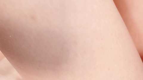 Media: Video of a close-up view of a pale-skinned person's arm and shoulder, showing subtle texture and a few minor imperfections, with soft lighting highlighting the natural skin tone.