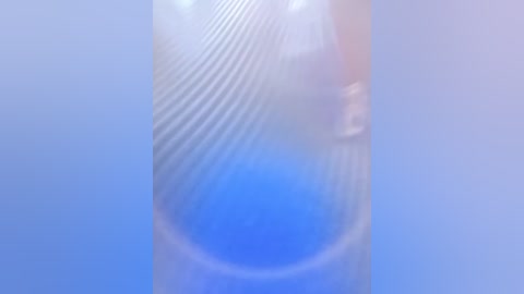 This is a soft-focus, abstract image featuring a central blue sphere with subtle concentric circles and a light blue background. The overall effect is dreamy and ethereal.