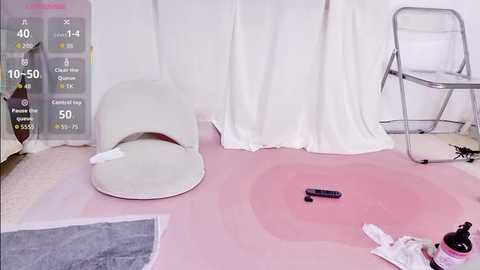 Video of a pink room with white furniture, including a chair and a cushioned armchair, with a grey rug, and a white table with a black candle and a white cloth.
