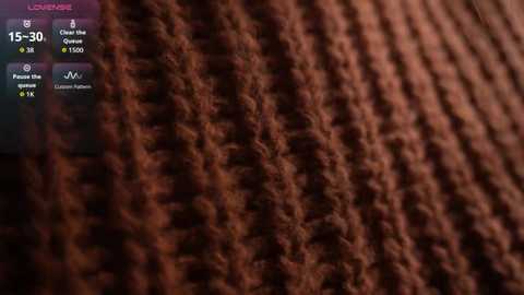 Video of a close-up, textured brown knitted fabric with visible stitches, set against a dark background.
