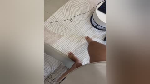 Video of a person standing on a light beige, ribbed bathmat in a modern bathroom, with a white round stool and a black lamp in the background.