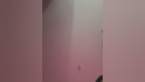 A close-up video of a beige wall with a small, circular hole near the center. The background is blurred, creating a soft focus effect. The image captures a minimalist, utilitarian aesthetic.