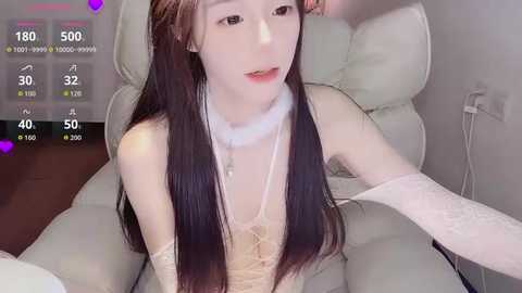 A video of a young, slender, fair-skinned Asian woman with long, straight brown hair and a white, lace choker. She sits in a white chair, with a digital overlay displaying social media stats.