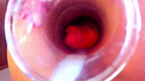 Close-up video of a brightly colored, translucent, red-and-white-striped cylindrical object resembling a candy or a toy, seen through a clear, round glass or plastic tube, possibly a telescope or microscope lens.
