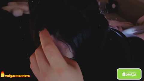 A close-up video of a man's hand touching a woman's face, with blurred background and watermark \"vulgarmanos\" at the bottom left.