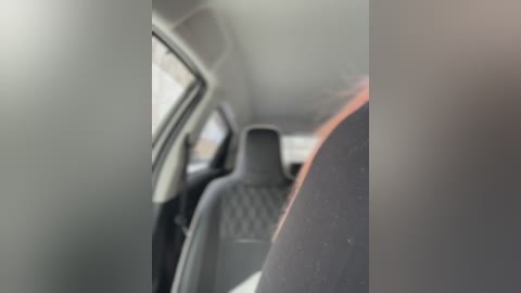 Video of a dimly lit car interior, showing a black leather seat with a quilted pattern. The image is slightly blurred, and the car window is partially visible, casting a soft reflection. The overall ambiance is calm and private.