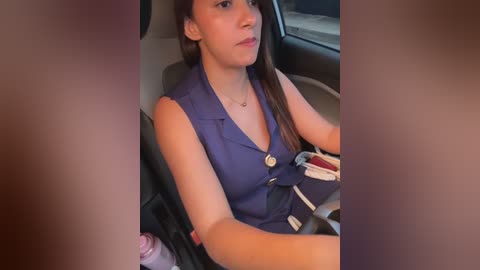 A video of a young Latina woman in a blue sleeveless dress, sitting in a car, holding a pink drink, with blurred faces in the foreground.