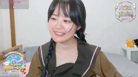A video of an East Asian woman with long black hair in braids, wearing a brown school uniform, smiling in a simple bedroom setting.