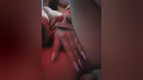 A close-up video of a hand with long, manicured nails and light skin tone, gently caressing a thigh, with a red and purple background, evoking a sensual and intimate atmosphere.