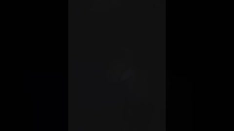 A video of a dark, vertical rectangular object against a black background, with subtle light reflections and a slightly textured surface.