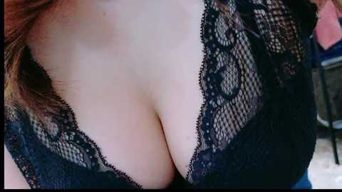 Close-up video of a light-skinned woman's cleavage, wearing a black lace bra with floral patterns, revealing ample cleavage.