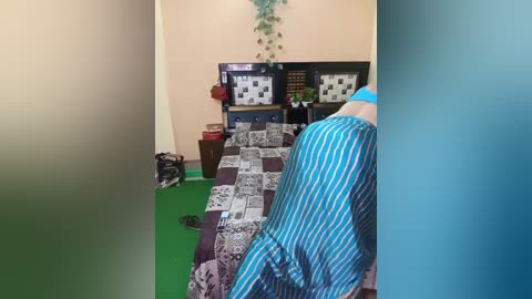 Media: Video of a child's bedroom with a striped bedspread, green carpet, bookshelves, a black and white cat, and a potted plant on a peach wall.