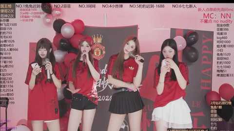 Video of four young Asian women in red shirts and black shorts, holding microphones, performing on stage with red balloons and a banner.