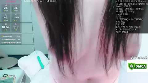 Video of a young woman's bare back, with dark, straight hair cascading down. She's in a modern, white room with a digital display showing health statistics. The image is from a live stream on the Wimbo app.