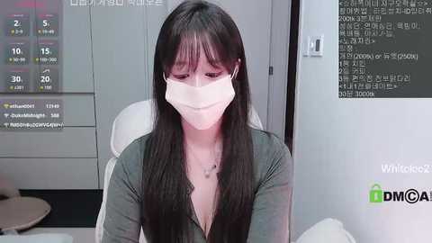 Video of a woman with long black hair, wearing a mask, sitting in a medical office, with a digital display and Korean text in the background.