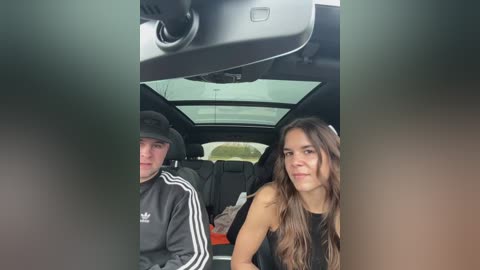 Media: Video of two people in a car; a man with a black cap and jacket, and a woman with long brown hair and a black top.
