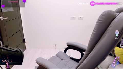 A video of a modern, minimalist office space featuring a gray ergonomic office chair, a white wall, and a black filing cabinet. The scene is well-lit with a light-colored wooden floor.