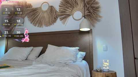 Video of a modern bedroom with a wooden bed, white linens, beige woven wall art, and a nightstand with a candle lamp. Digital clock overlay displays 21:24, and pink flower overlay.