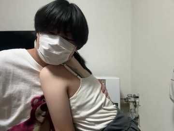 Video of an Asian woman with straight black hair and glasses, wearing a white tank top and face mask, hugging a smaller Asian girl in a white tank top, in a clinical room with white walls and medical equipment.