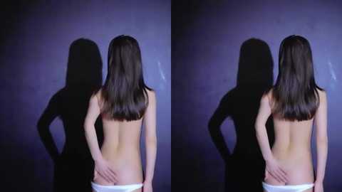 Media: Video of a topless woman with long brown hair, facing away, standing against a dark background, with her hands on her hips, wearing white panties.