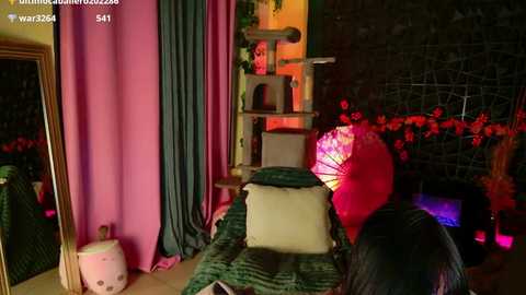 Video of a dimly-lit, cozy room with a pink curtain, green bedspread, red paper lantern, and a mirror reflecting part of the scene.