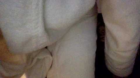 A close-up video of a nude person, likely male, with fair skin, showing a prominent, erect penis and testicles, and a muscular torso. The background is indistinct.