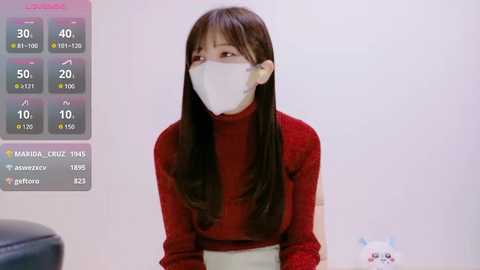 Media: Video of an East Asian woman with long black hair, wearing a white mask and red sweater, sitting indoors against a white background. Weather app on left screen shows 40% chance of rain.