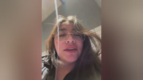 Media: Video of a young woman with light skin, shoulder-length brown hair, and glasses, caught in a moment of surprise or shock, possibly in a bathroom setting.