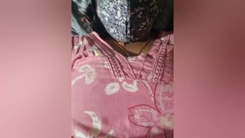 Video of a pink floral dress with embroidered neckline, lying on a patterned gray and white pillow. The fabric appears soft and smooth.