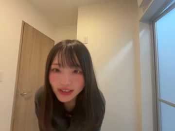 Media: A video of a young Asian woman with long black hair and light skin, wearing a black shirt, leaning forward with a playful expression, indoors with beige walls, a wooden door, and a window.