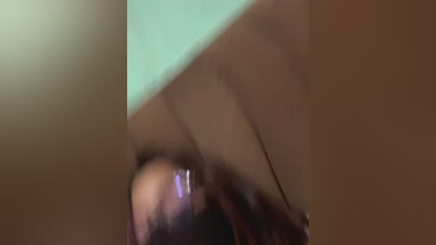 A blurred, low-angle video of a person lying on their back, with a blurred, greenish background. The image has a soft focus, making details difficult to discern.