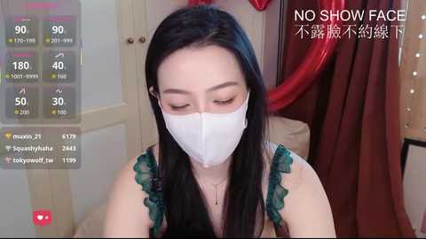 A video shows an Asian woman with long black hair, wearing a white surgical mask and green lace top, indoors with a red curtain and digital stats overlay.