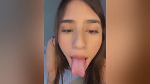 Video of an Asian woman with long black hair, light skin, and dark eyes, licking her lips. The background is blurred, featuring a soft focus on her face.