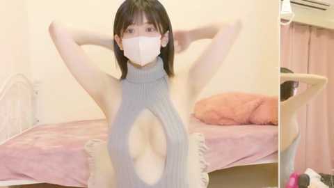 Video of an Asian woman with fair skin, wearing a gray, ribbed, sleeveless sweater with a large cutout revealing her chest, posing in a pink bedroom with a white metal bed and pink curtains.