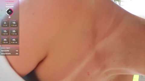 A close-up video of a woman's bare back with tan lines, showing a clear distinction between the tanned and untanned areas. The background is blurred and indistinct.
