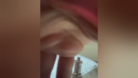 A blurred video shows a close-up of a penis, with a bottle of lubricant partially visible in the background. The image is slightly out of focus, making it difficult to discern specific details.