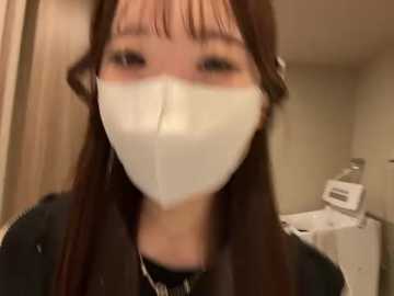 Video of an Asian woman with straight, shoulder-length brown hair, wearing a white face mask, black shirt, and a silver necklace. Background shows a white bathroom sink and mirror.
