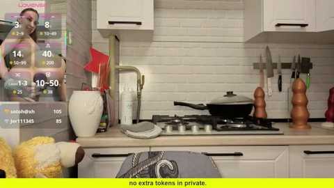 Video of a modern, white-tiled kitchen with a stove, utensils, and cooking utensils, featuring a digital overlay of a woman's face and calorie count, with a yellow overlay at the bottom.