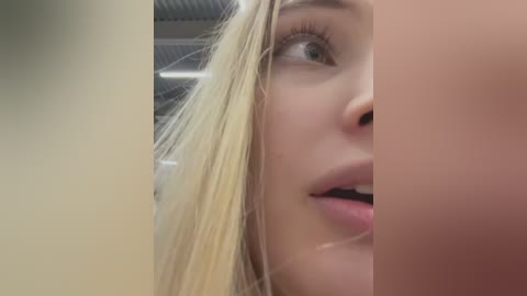 Video of a close-up, cropped face with light blonde hair and fair skin, focusing on the lips and nose. Background is blurry and out of focus.