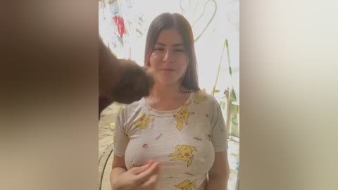 Video of a Latina woman with long dark hair, wearing a yellow Pikachu t-shirt, with a dark-skinned man's erect penis in the foreground.