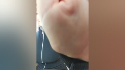 Video of a close-up of a person's face, partially obscured by a blue jacket with white piping, and a blurred background.