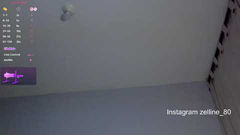 A video of a dimly lit, white-walled room with a live stream camera on a tripod, displaying a drone view of the room and a purple light.