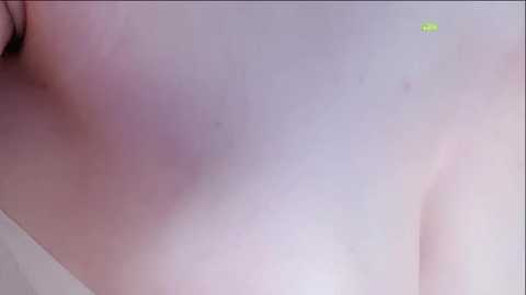 A close-up video of a person's bare back, showing pale skin with a faint pinkish hue and a few small moles. The background is blurred, suggesting an indoor setting.