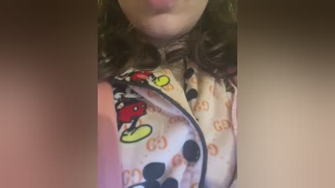 Video of a woman's face and chest, wearing a patterned, light-colored nightgown with cartoon characters and \"GUCCI\" logos, lips slightly parted.