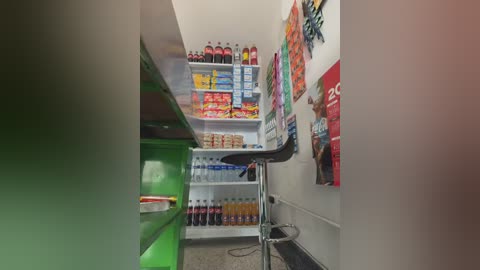 Video of a small, well-stocked pantry with white walls, green cabinets, and shelves filled with various beverages, snacks, and canned goods.