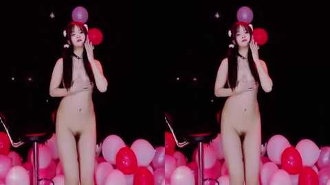 Video of a nude Asian woman with long black hair, wearing a red flower crown, standing amidst red and white balloons.