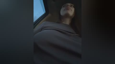 Video of a pregnant woman with a large belly, lying down in a car, looking up with a serene expression.