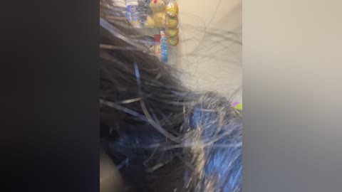 A video showing a messy pile of black, silver, and gold tinsel strands, a small, colorful toy, and a plastic bottle, scattered on a light-colored surface, possibly a table or floor.