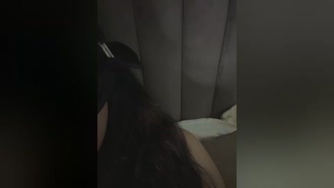 A dimly lit video shows a person with long dark hair kneeling in a bathtub, partially obscured by a curtain. The image is low-resolution and slightly blurred.